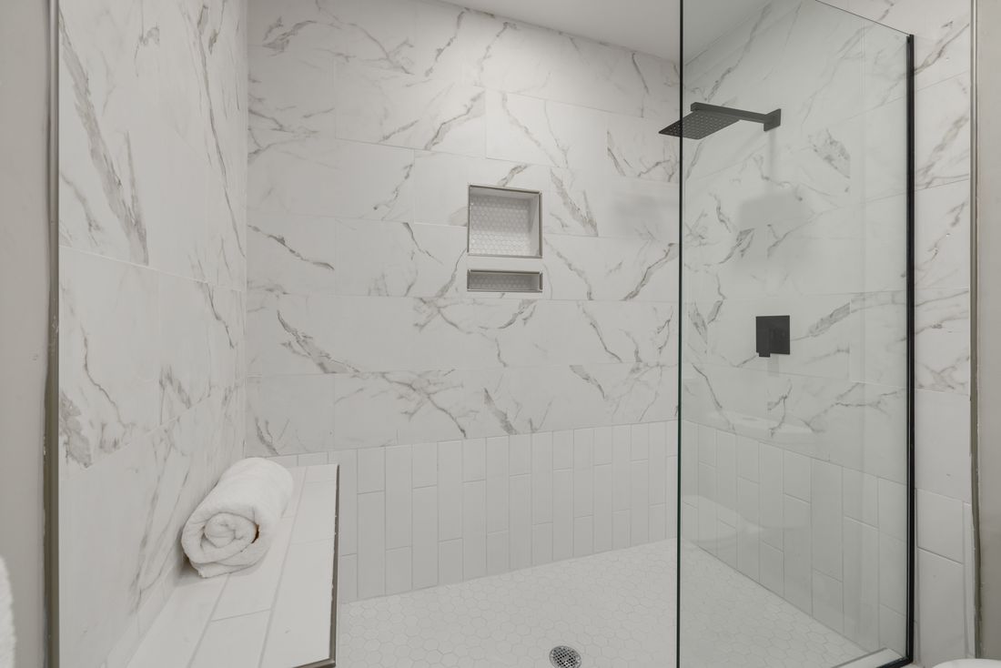 High-end frameless glass shower enclosure in a marble bathroom