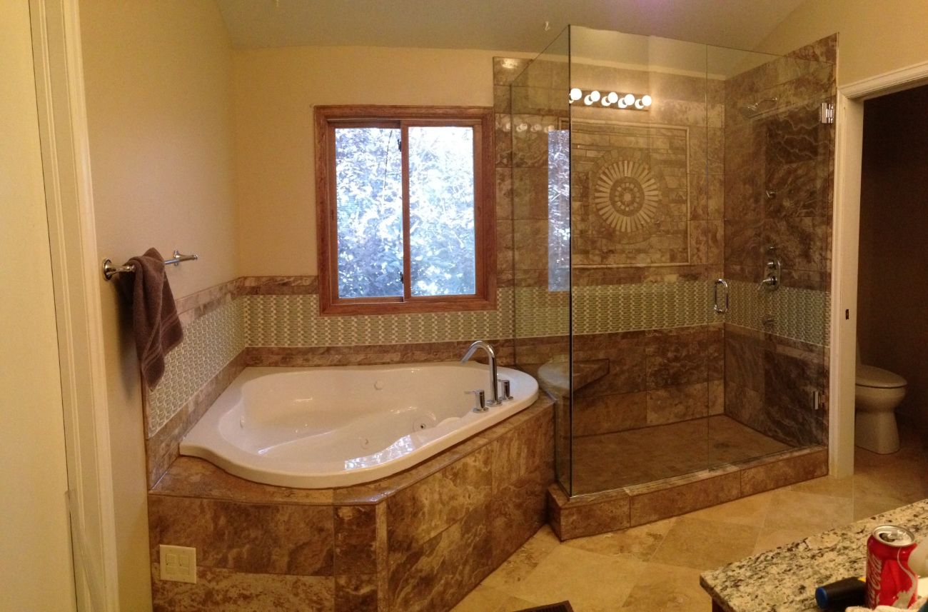 Frameless glass shower enclosure with travertine tile